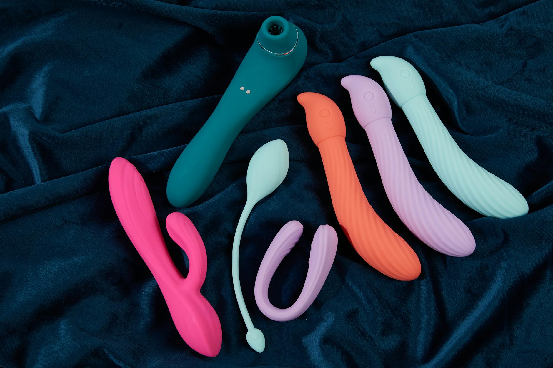 A stylish teal lemon vibrator resting on smooth white silk fabric